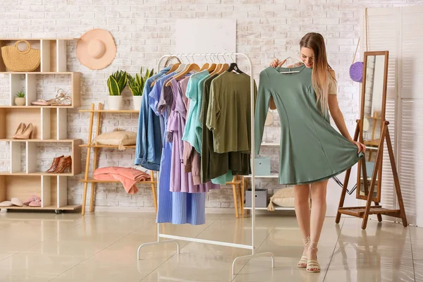 Young woman choosing clothes in dressing room — Stock Photo, Image