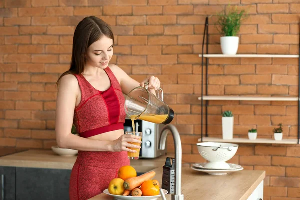 Young sporty woman preparing healthy vegetable juice in kitchen — Stock Photo, Image