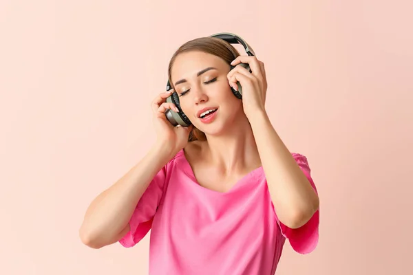 Mooie jonge vrouw luisteren naar muziek op kleur achtergrond — Stockfoto