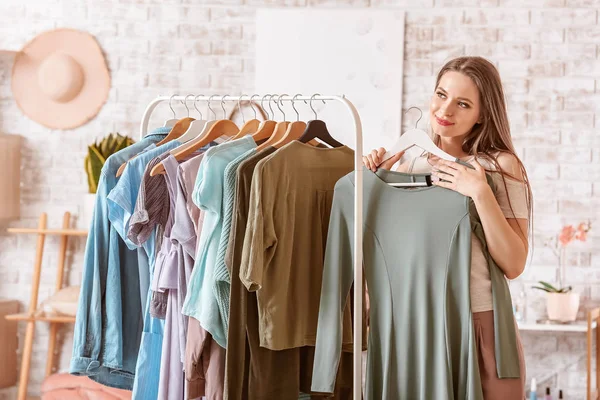 Mujer joven eligiendo ropa en vestidor — Foto de Stock