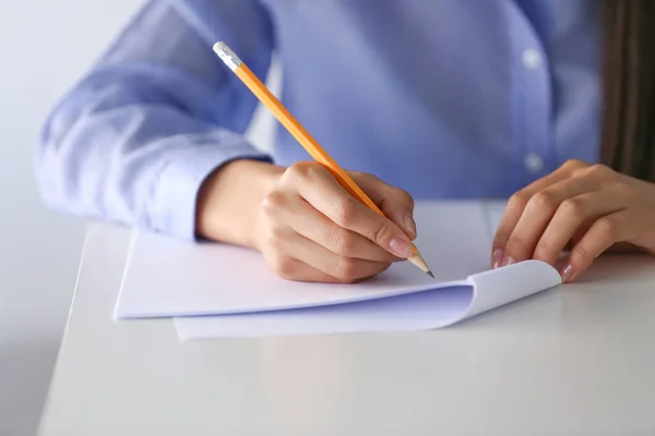 Young female student writing on sheet of paper, closeup — Stock Photo, Image