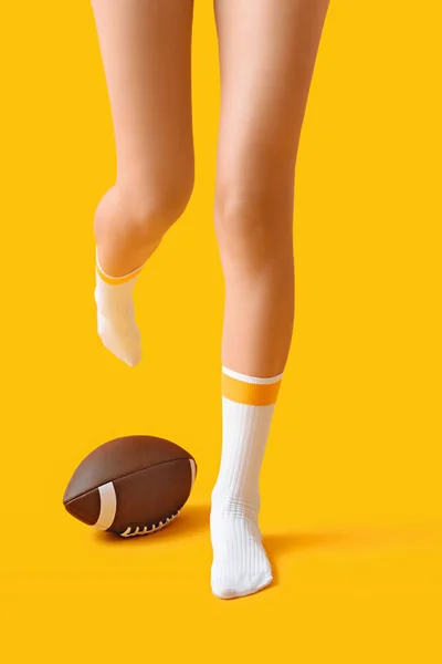 Piernas de mujer joven en calcetines y con pelota de rugby sobre fondo de color — Foto de Stock