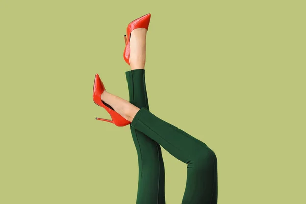 Gambe di giovane donna in scarpe con tacco alto e pantaloni su sfondo di colore — Foto Stock