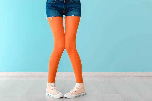 Stylish young woman in shoes and tights near color wall — Stock Photo, Image