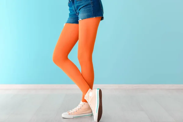 Mujer joven con estilo en zapatos y medias cerca de la pared de color —  Fotos de Stock