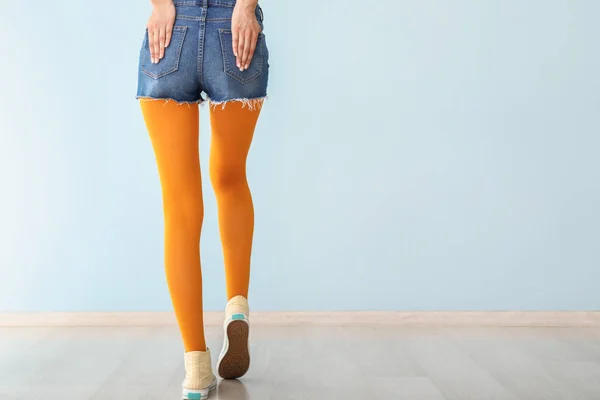 Mujer joven con estilo en zapatos y medias cerca de la pared de color — Foto de Stock