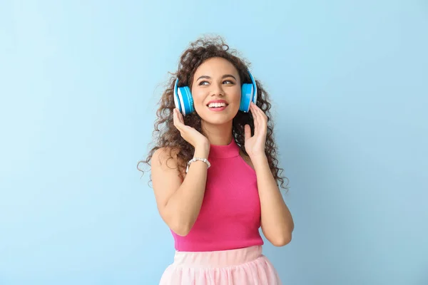 Happy African-American woman listening to music on color background — Stock Photo, Image