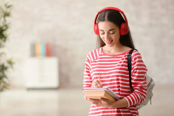 Young female student listening to music indoors — Stock Photo, Image