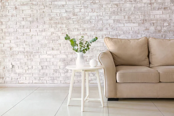 Sofá elegante con mesa cerca de la pared de ladrillo en la sala de estar — Foto de Stock