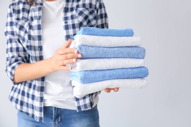 Hafif arka planda temiz havlu yığını ile güzel genç kadın