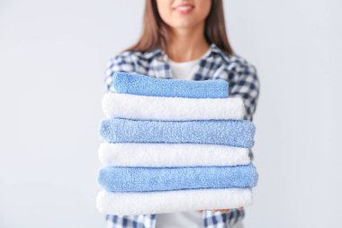 Hafif arka planda temiz havlu yığını ile güzel genç kadın