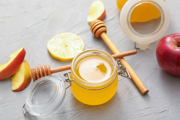Gri arka plan üzerinde tatlı bal, elma ve limon Kavanoz
