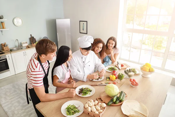 Asiatischer Koch und eine Gruppe junger Leute während eines Kochkurses — Stockfoto