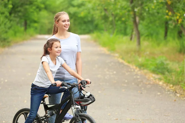Mãe ensinando sua filha a andar de bicicleta ao ar livre — Fotografia de Stock