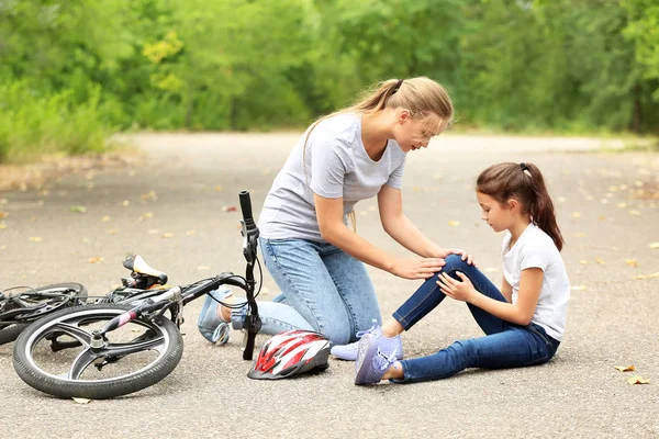 Mãe ajudando sua filhinha depois de cair de bicicleta ao ar livre — Fotografia de Stock