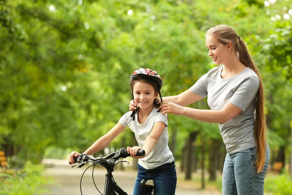 Mãe ensinando sua filha a andar de bicicleta ao ar livre — Fotografia de Stock