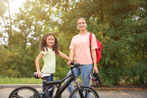 Woman and her little daughter with bicycle outdoors — Stock Photo, Image