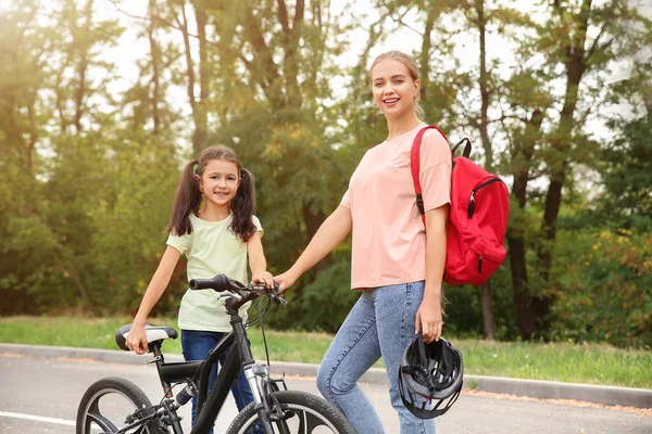 Mulher e sua filhinha com bicicleta ao ar livre — Fotografia de Stock