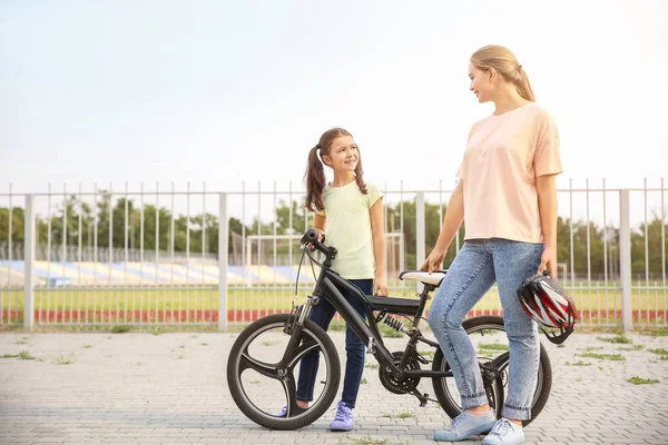 Woman and her little daughter with bicycle outdoors — Stock Photo, Image
