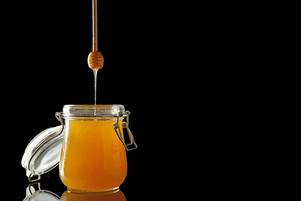 Tarro y jarra con sabrosa miel sobre fondo oscuro — Foto de Stock