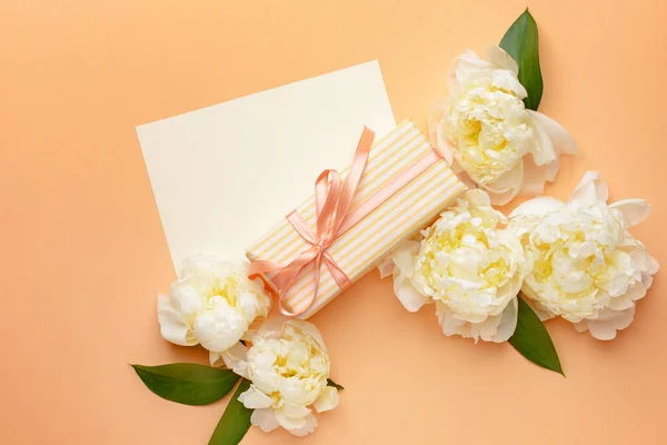 Gift box, blank card and beautiful flowers on color background — Stock Photo, Image