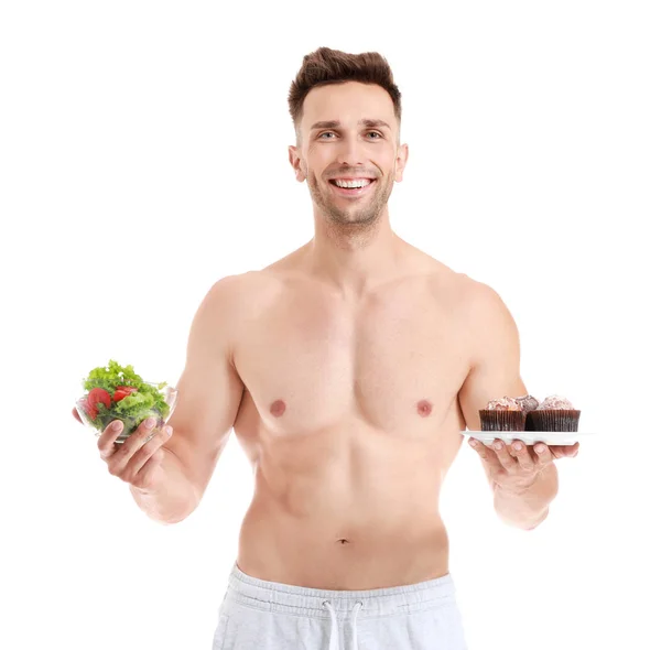 Красивый мускулистый мужчина с салатом и десертом на белом фоне. Концепция потери веса — стоковое фото