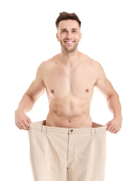 Knappe gespierde man in losse broek op witte achtergrond. Gewichtsverlies concept — Stockfoto