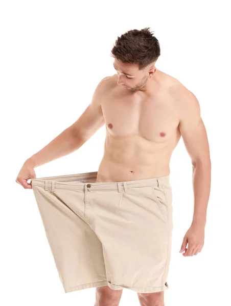 Handsome muscular man in loose pants on white background. Weight loss concept