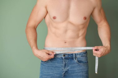 Renkli arka planda ölçüm bandı ile yakışıklı kaslı adam. Kilo kaybı kavramı