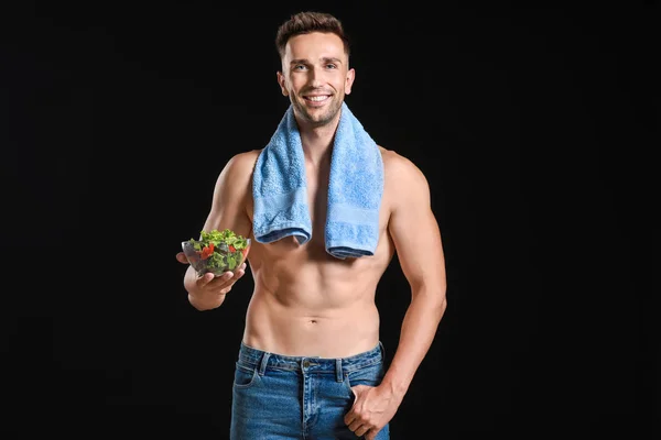 Handsome muscular man with salad on dark background. Weight loss concept — Stock Photo, Image