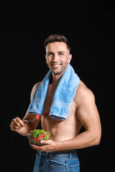 Hombre musculoso guapo con ensalada sobre fondo oscuro. Concepto de pérdida de peso — Foto de Stock