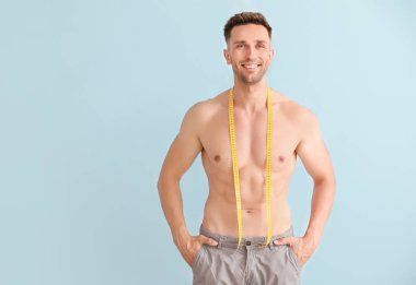 Renkli arka planda ölçüm bandı ile yakışıklı kaslı adam. Kilo kaybı kavramı