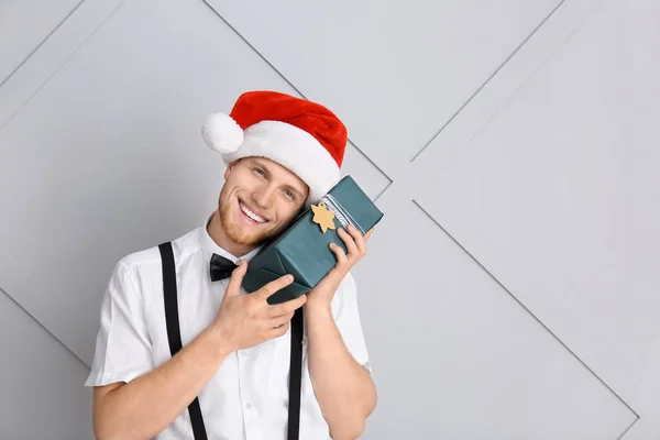 Young man with Christmas gift box on light background — Stock Photo, Image