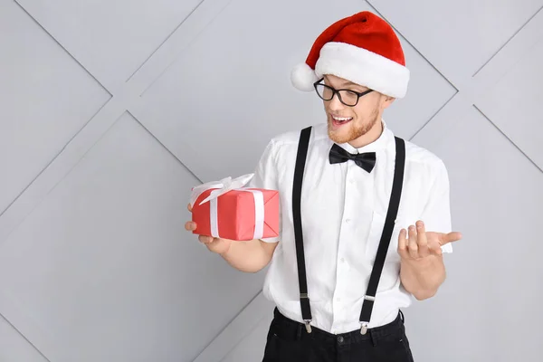 Young man with Christmas gift box on light background — Stock Photo, Image