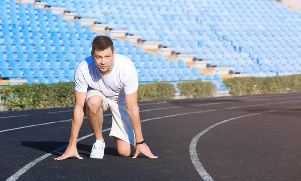 Sporty man in crouch start position at the stadium — Stock Photo, Image