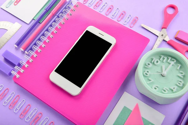 Mobile phone and stationery on color background — Stock Photo, Image