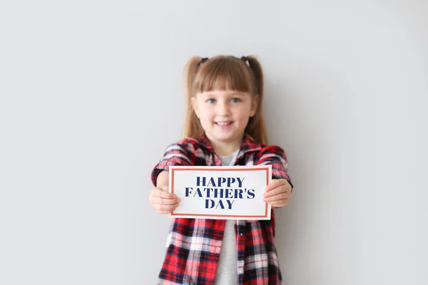Schattig klein meisje met wenskaart voor vaderdag op lichte achtergrond — Stockfoto