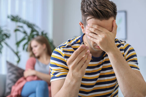 Sad man with wedding ring at home. Concept of divorce