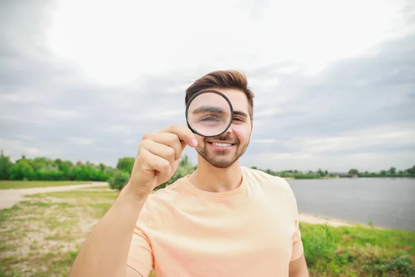 Uomo con lente d'ingrandimento che studia la natura all'aperto — Foto Stock