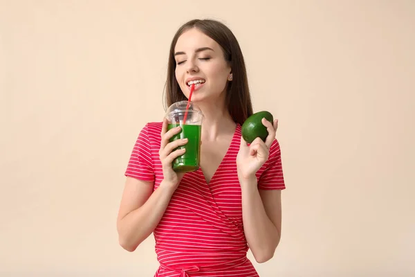 Young woman with avocado drinking healthy vegetable juice on light background — Stock Photo, Image