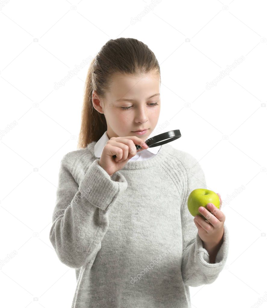 Little girl with magnifying glass and apple on white background