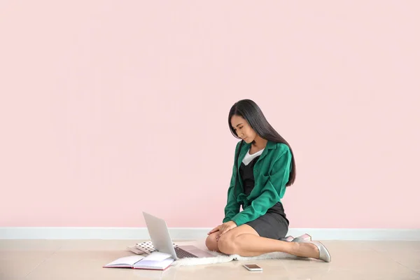 Jonge Aziatische Blogger met laptop zittend in de buurt van kleur muur — Stockfoto