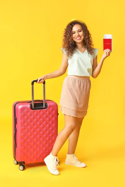 Happy African-American woman with luggage, passport and ticket on color background — Stock Photo, Image