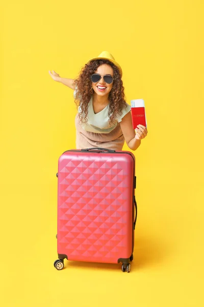 Happy African-American woman with luggage, passport and ticket on color background — Stock Photo, Image