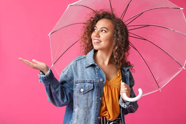 Stylish African-American woman with umbrella on color background — Stock Photo, Image