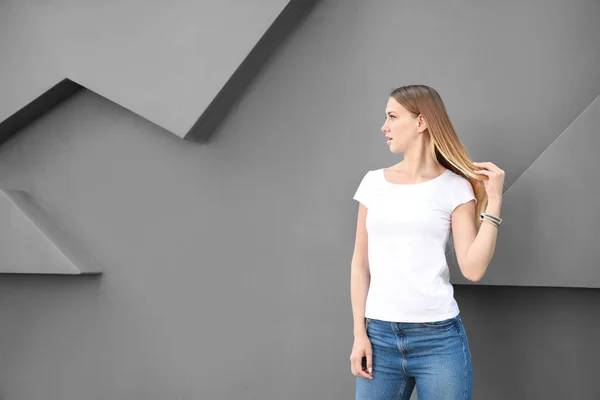 Woman in stylish t-shirt near grey wall — Stock Photo, Image