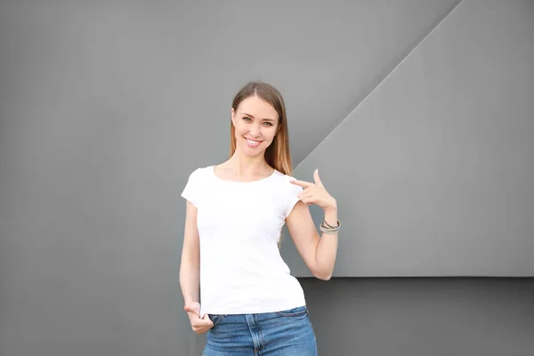 Donna in elegante t-shirt vicino alla parete grigia — Foto Stock