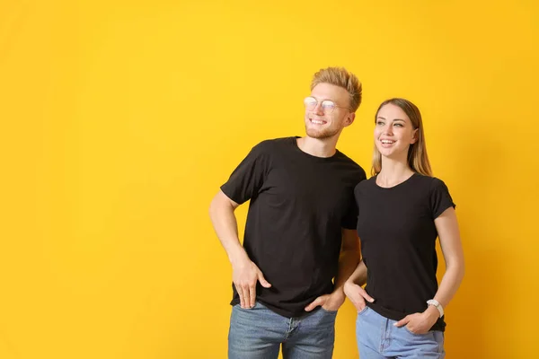 Casal em camisetas elegantes no fundo da cor — Fotografia de Stock