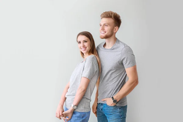 Casal em camisetas elegantes no fundo claro — Fotografia de Stock