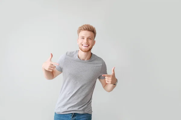 Man pointing at his t-shirt against light background — Stock Photo, Image